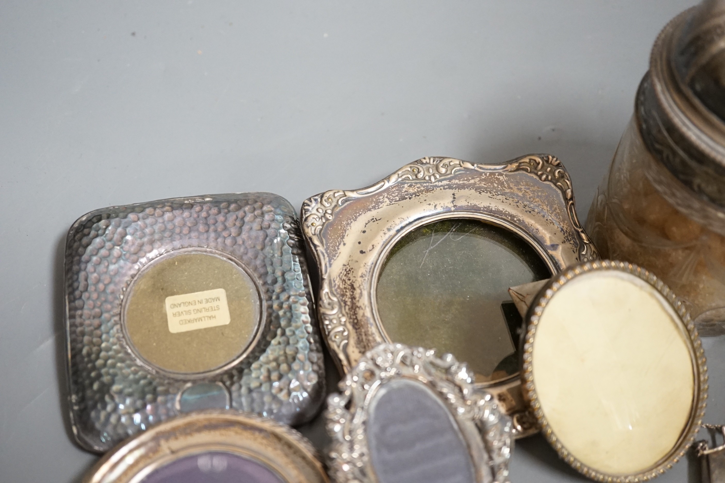 Four small silver mounted photograph frames, one brass frame, a silver lidded jar and one other and a 925 handbag pill box.